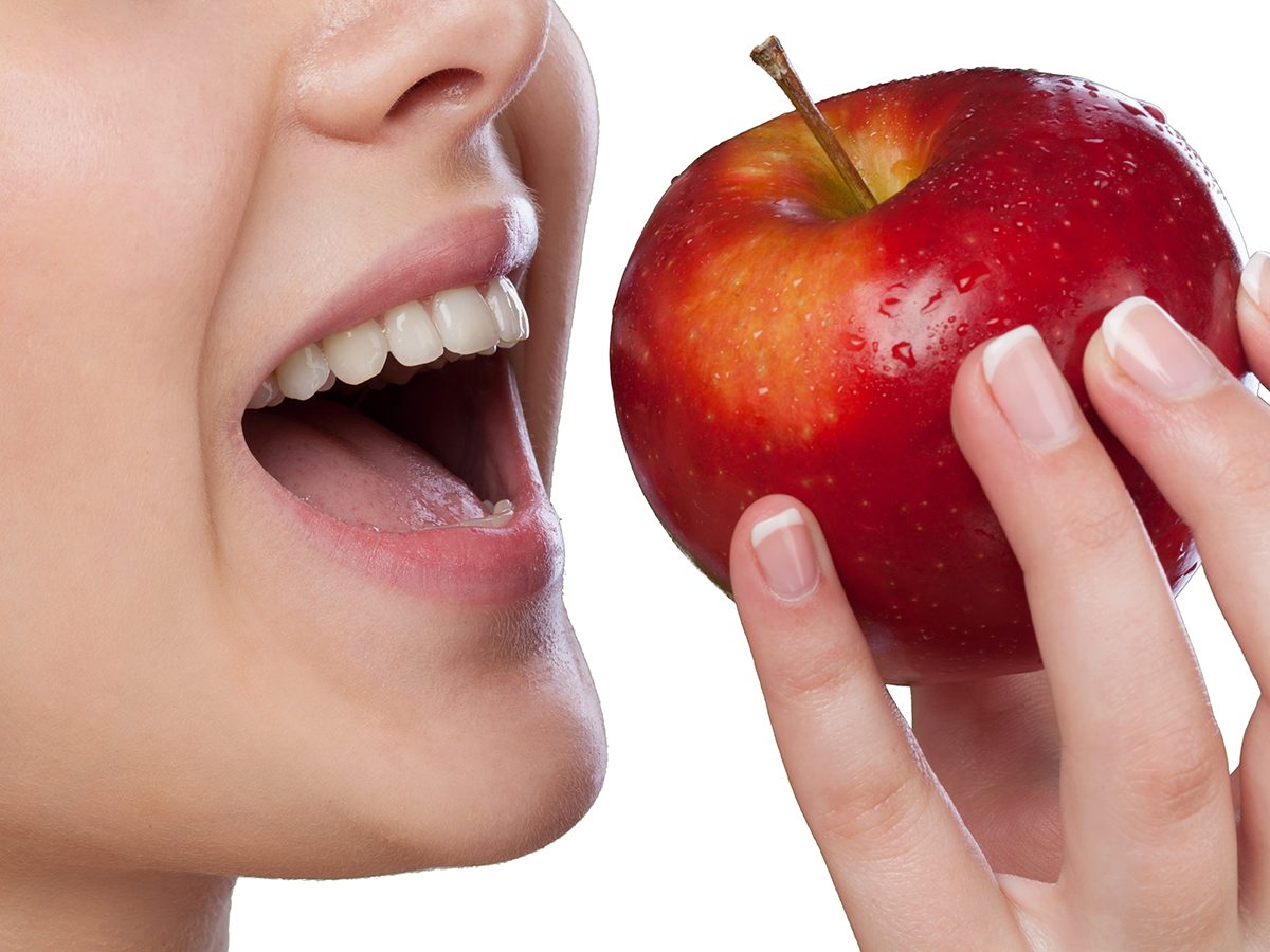 Dents blanches qui s'apprêtent à croquer dans une pomme. pomme.